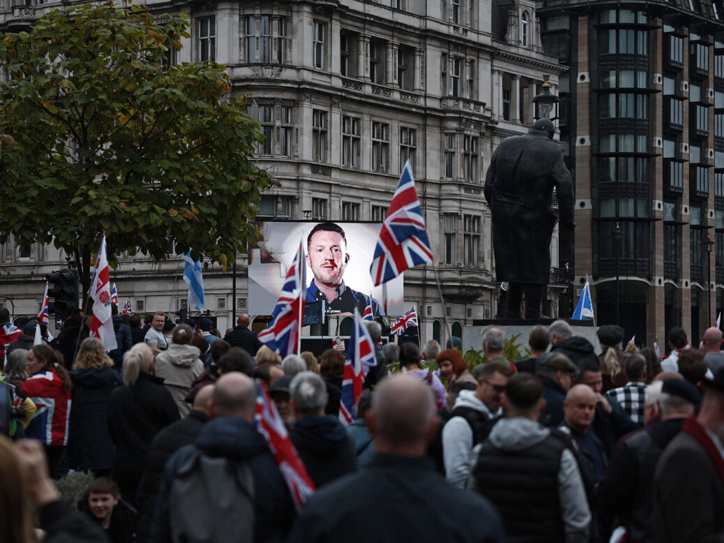 A crowd gathers at the “Unite the Kingdom” rally in London, with far-right activist Tommy Robinson poster visible
