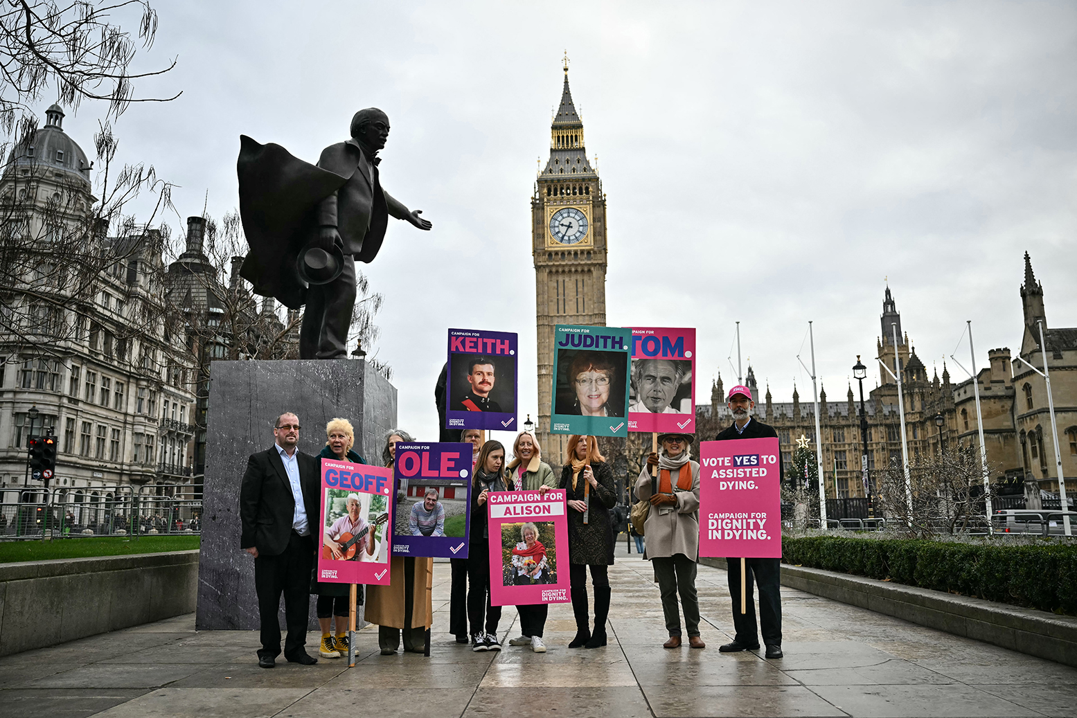 Terminally ill campaigners and families hold posters of loved ones in Parliament Square London supporting the assisted dying bill December 2025